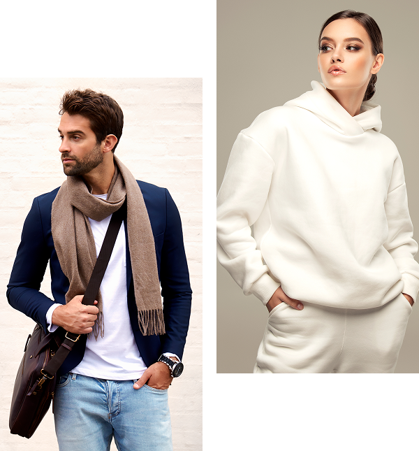 Man in blue blazer and scarf stands with a bag; woman in white hoodie gazes sideways.