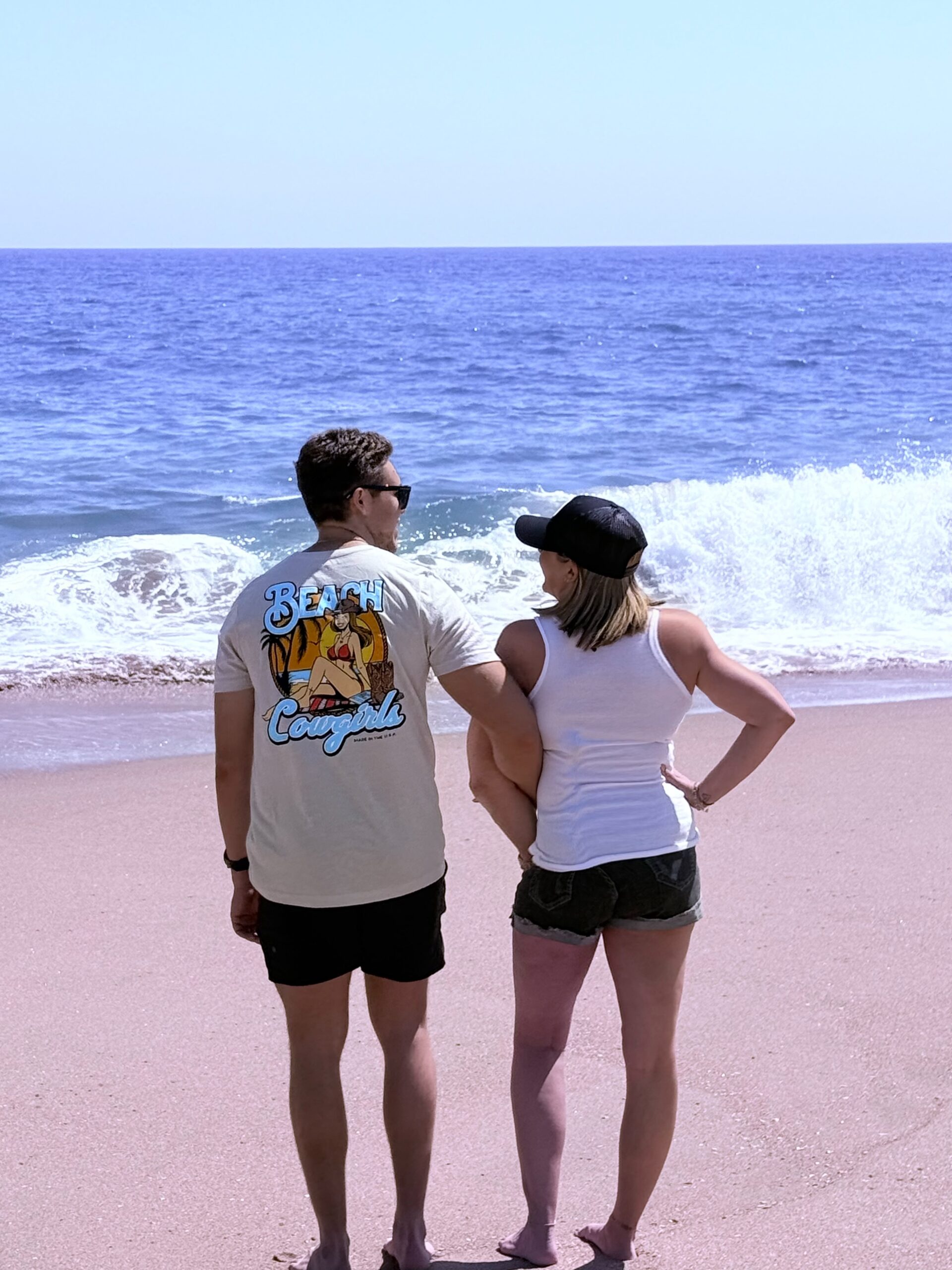IMG_7645 A man and woman standing on the beach looking at the ocean.